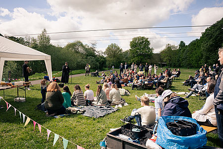Menschen feiern draußen an der Lahn einen Gottesdienst