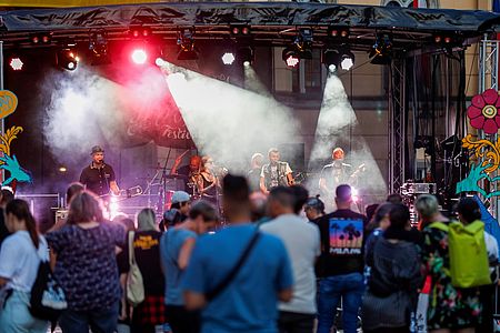 Band steht auf der Bühne, viele Menschen schauen zu