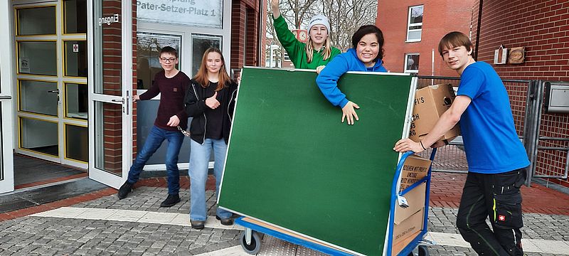 Schüler transportieren grüne Tafel